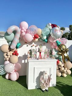 an outdoor party with balloons and decorations on the grass, including santa clause balloon wall