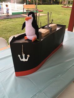 a stuffed penguin sitting on top of a boat shaped like a pirate's ship