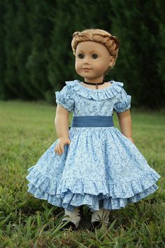 a doll is standing in the grass wearing a blue dress