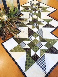 a quilted table runner on top of a wooden table next to a vase with flowers