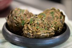 there are some artichokes in a bowl on the table top, ready to be eaten