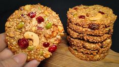 a person holding up some cookies with fruit and nuts on top, next to each other