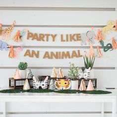 a party like an animal banner and decorations on a white table with plants, potted plants