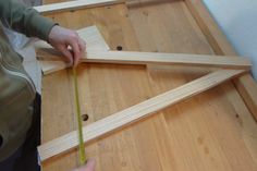 a person measuring the length of a wooden frame