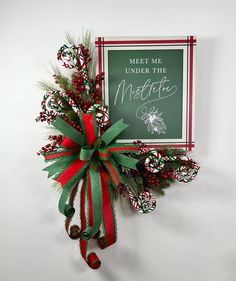 a christmas wreath hanging on the wall next to a sign that says meet me under the mistlet