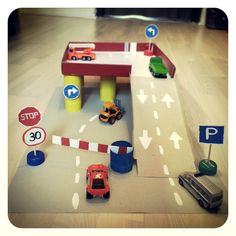 a play area with cars, trucks and signs on the floor for children to learn how to drive