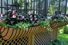 three planters filled with pink and white flowers sitting on a wooden bench in front of a house