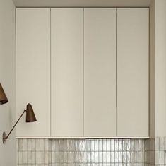 a kitchen with white cupboards and a black lamp on the wall above the sink