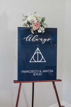 a harry potter wedding sign with flowers on the front and back, hanging from a wooden easel