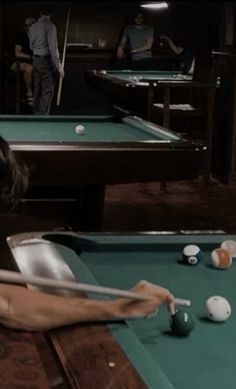 a woman sitting at a pool table in front of a pool ball rack and cues