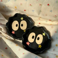 two black plates with faces painted on them sitting on a white cloth covered tablecloth