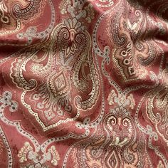 a red and gold paisley print fabric with silver accents on the bottom half of it