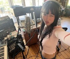 a woman with long black hair standing in front of a recording equipment set up on a hard wood floor