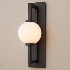 a light that is on the wall next to a white wall lamp with a black frame