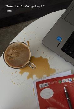 a cup of coffee sitting on top of a white table next to a laptop computer