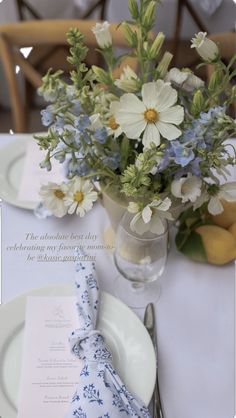 there is a vase with flowers on the table next to plates and utensils