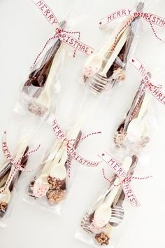 several forks and spoons wrapped in cellophane with red ribbon on white surface