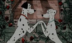 two dalmatian dogs playing with each other in front of a rose covered wall