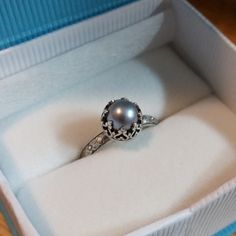 Timeless and sophisticated, this vintage style gray pearl engagement ring is reminiscent of the Edwardian era when fine metalwork was designed with intricate details and delicate settings fashioned to resemble patterns of fine lace. Handcrafted from recycled sterling silver, a lightly oxidized floral band is set with a luminous 6.5-7mm cultured gray freshwater pearl in a filigree heart-wire crown setting that is hand-patinaed and polished to a soft shine. This pearl ring would make a unique non- Wire Crown, 14kt Gold Jewelry, Floral Wedding Bands, Filigree Heart, Pearl Engagement Ring, Edwardian Style, Sterling Silver Engagement Rings, Local Jewelry, Edwardian Era