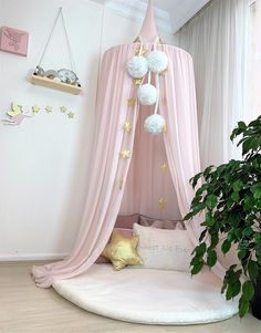 a pink canopy bed with pom - poms hanging from it's sides