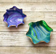 two colorful dishes sitting on top of a wooden table next to each other and one has a leaf shaped bowl in the middle