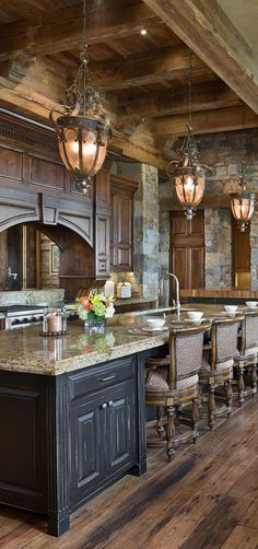 a large kitchen with an island in the middle and two chandeliers hanging from the ceiling