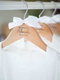 two wooden hangers with names on them are attached to white shirts that say bridesmaid and bridal