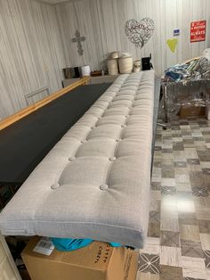 a long gray bench sitting in the middle of a room with boxes on the floor