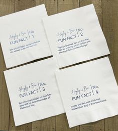 four white napkins with blue writing on them sitting on a wooden table next to each other