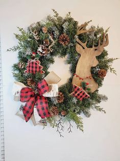 a christmas wreath hanging on the wall with deer head and pineconing around it