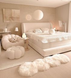 a large white bed sitting in a bedroom next to a chair and ottoman on top of a hard wood floor