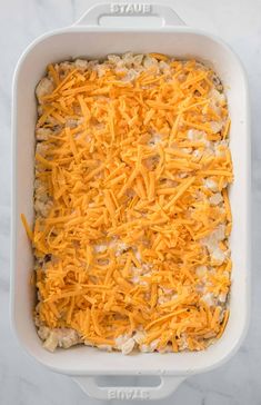 a casserole dish with cheese on top and ground beef in the bottom, ready to be baked