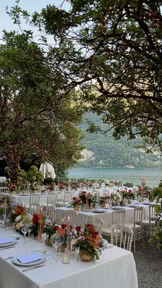 an outdoor dining area with tables and chairs set up for formal function overlooking the water