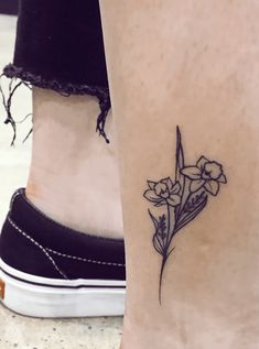 a woman's foot with a small flower tattoo on the left side of her leg