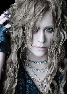 a woman with long curly hair and leather gloves on her shoulder is posing for the camera