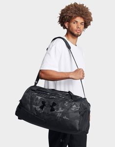 a man holding a black under armour duffle bag