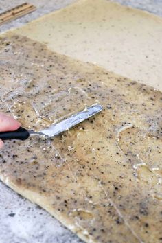 a person using a knife to cut something on a piece of paper that is covered in dirt