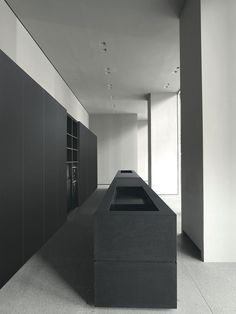 a black and white photo of a long counter in an empty room with shelves on the wall