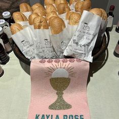 bread rolls in paper bags sitting on top of a table next to bottles of wine