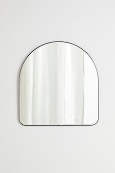 an oval mirror hanging on the wall with a white background and black trim around it