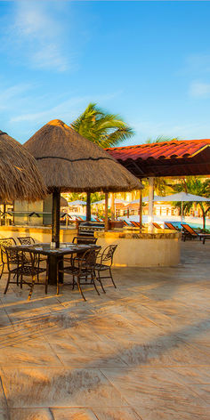 an outdoor dining area with thatched umbrellas and tables