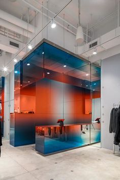 an office with glass partitions and clothes on display in the middle of the room