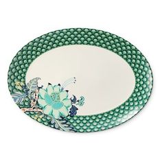 a green and white plate with a flower on the rim, sitting on a white surface