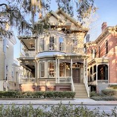 an old victorian house with many windows and balconies on the second floor is surrounded by trees