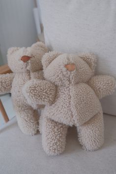 three teddy bears are sitting on the back of a chair with their arms around each other