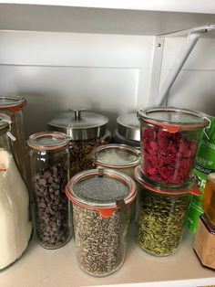 there are many different types of food in the jars on the shelf next to each other