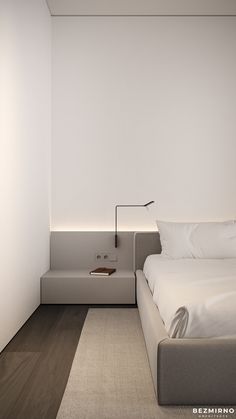 a bed sitting next to a white wall in a bedroom on top of a hard wood floor