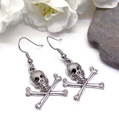 Dangly earrings with silver tone skull and bones charms. The earrings are ca 40mm (1.57 inches) long including hooks. Silver coloured hooks that comply with strict regulations for low nickel and lead content in jewellery. Bone Colored Metal Earrings For Pierced Ears, Nickel-free Skull Earrings In Punk Style, Nickel Free Metal Skull Earrings, Metal Skull Earrings With Ear Wire, Skull-shaped Metal Earrings With Ear Wire, Silver Skull Earrings With Skull Print, Skull Shaped Metal Earrings, Silver Skull Earrings With Ear Wire, Skull And Crossbones