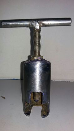 a metal object that is on top of a white table with a screwdriver attached to it