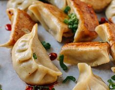 some dumplings are sitting on a piece of parchment paper with garnishes